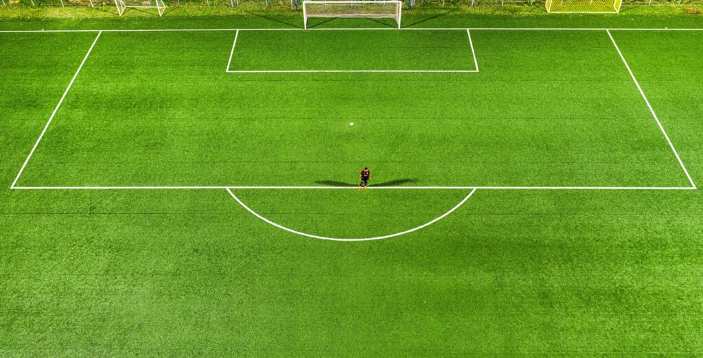 Aerial view of a football field with a goal net, surrounded by lush green grass.