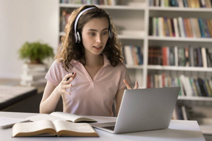 Girl with headphones attending online PTE classes on laptop